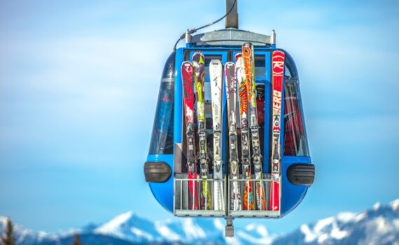Gondola wyciągu z zewnętrznym stelażem wypełnionym nartami, w tle szczyty gór